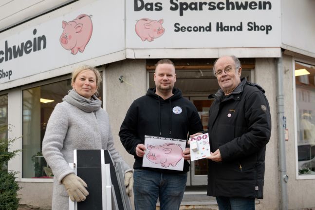 Günther Kerchner vom NIB, Sandra Leifheit vom afz und Nico vom Secondhand Laden Sparschwein stehen vorm Ladengeschäft und übergeben eine Rampe und Serviceklingel
